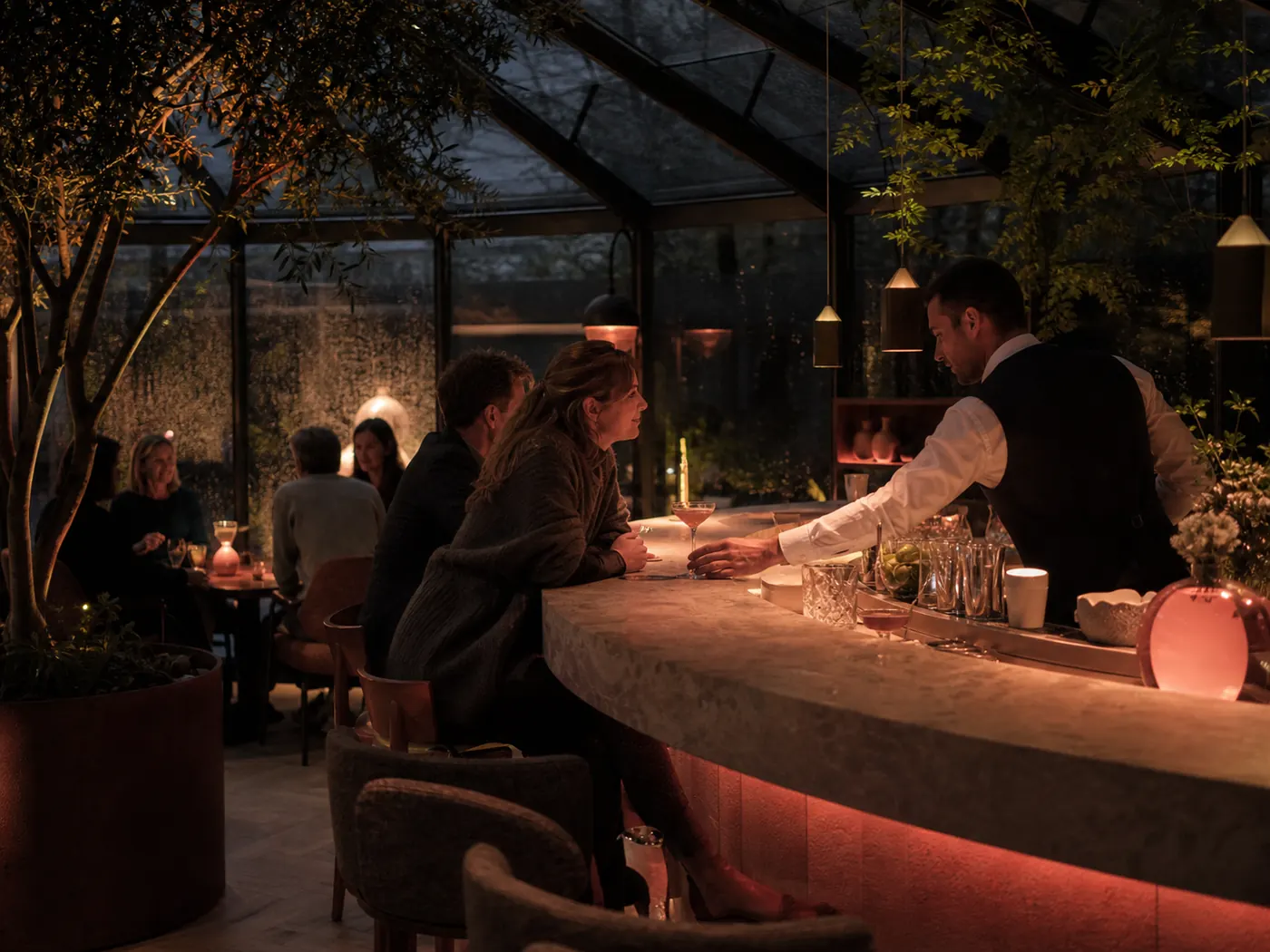 Koraalkleurige hotelbar onder glas met een rustig gezelschap